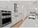 Modern kitchen featuring built-in double oven, cooktop, and center island with stone countertops at 9271 Rally Spring Loop, Wesley Chapel, FL 33545