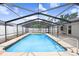 A screened-in pool with clear blue water is surrounded by a concrete deck and a white fence in the background at 1017 Cameo Crest Ln, Valrico, FL 33596