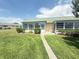 Charming single-story home featuring a well-manicured front lawn with sidewalk and lush landscaping at 102 Cambridge Trl # 230, Sun City Center, FL 33573