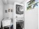 A bright laundry room with stacked washer and dryer and a utility sink at 1119 Eau Claire Cir, Tampa, FL 33619
