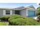 Inviting home exterior with lush green bushes, blue garage door and complementing trim at 11845 Autumn Creek Dr, Riverview, FL 33569