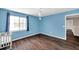 Bright blue bedroom with wood floors, a crib, and natural light from the window at 1204 Rinkfield Pl, Brandon, FL 33511