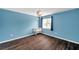 Cozy blue bedroom with a crib, window, and dark wood-look floors at 1204 Rinkfield Pl, Brandon, FL 33511