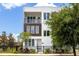 Modern three-story townhome featuring white exterior, dark trim, and a black metal fence at 121 E Warren Ave # 4, Tampa, FL 33602