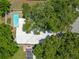 An aerial shot captures a bright pool next to a well-kept single-story house embraced by the shade of full-grown trees at 1211 Stony Brook Ln, Dunedin, FL 34698