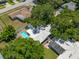 An inviting pool highlights this aerial view of a well-maintained single-story home surrounded by lush, mature landscaping at 1211 Stony Brook Ln, Dunedin, FL 34698