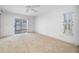 This carpeted bedroom features a ceiling fan, a sliding glass door, and natural light at 1211 Stony Brook Ln, Dunedin, FL 34698