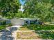 Charming single-story home with attached garage, mature landscaping, and beautiful curb appeal on a sunny day at 1211 Stony Brook Ln, Dunedin, FL 34698