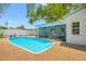 Sparkling blue pool with screened-in lanai, metal ladder and hardscape deck surrounded by a white fence at 1211 Stony Brook Ln, Dunedin, FL 34698