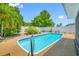 Sparkling pool with blue tile, metal ladder and hardscape deck surrounded by a white fence and manicured trees at 1211 Stony Brook Ln, Dunedin, FL 34698