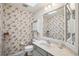 Small bathroom with a toilet, sink, vanity, and patterned wallpaper at 12433 Kelso Rd, Thonotosassa, FL 33592