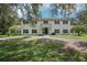 A charming two-story white home boasts mature trees, black shutters, and a circular driveway at 12433 Kelso Rd, Thonotosassa, FL 33592