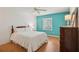 Bright main bedroom featuring a turquoise accent wall, parquet floors, and white trim at 12433 Kelso Rd, Thonotosassa, FL 33592