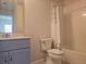 Bathroom featuring a vanity with a large mirror and a toilet under a shower with a leaf-patterned curtain at 19643 Shady Oak Dr, Land O Lakes, FL 34638