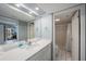 Well-lit bathroom features a sleek vanity with a large mirror, and a shower with a crisp, white shower curtain at 19925 Gulf Blvd # 407, Indian Shores, FL 33785