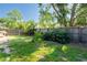 Fenced backyard with green grass and tropical foliage, offers privacy and space for recreation at 2024 Glen Forge St, Brandon, FL 33511