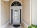 A pristine entryway with a storm door, sidelights, decorative transom window and neutral walls at 2216 Evans Rd, Clearwater, FL 33763