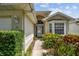 A welcoming entryway with a storm door, sidelights, colorful landscaping and a bay window at 2216 Evans Rd, Clearwater, FL 33763
