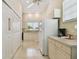 Galley kitchen with white cabinetry, appliances, tile floor, and a fire extinguisher mounted by the door at 2216 Evans Rd, Clearwater, FL 33763