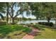 Serene water view with a brick path, lush lawn, and mature trees creating a peaceful backyard setting at 2617 Heatherwood Dr, Tampa, FL 33618