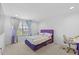 A bright bedroom featuring a window, neutral carpet, and vibrant purple accents, with ample space at 33255 Kateland Dr, Wesley Chapel, FL 33545