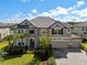 Stately two-story home featuring a stone facade, manicured lawn, paver driveway and a three-car garage at 33255 Kateland Dr, Wesley Chapel, FL 33545