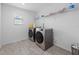 Bright laundry room with modern washer and dryer, tiled floors, and ample shelf space at 33255 Kateland Dr, Wesley Chapel, FL 33545