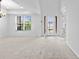 Open-concept living room featuring large window, tray ceiling and glass panel entry doors at 33255 Kateland Dr, Wesley Chapel, FL 33545