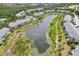 An aerial view of the homes, pool, and lake, surrounded by lush greenery in the neighborhood at 404 Laurel Lake Dr # 101, Venice, FL 34292