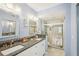 Bathroom with dual sinks, a large mirror, and a glass-enclosed tiled shower at 404 Laurel Lake Dr # 101, Venice, FL 34292