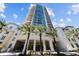 Luxury high-rise exterior featuring a modern design, blue windows, and palm tree-lined entrance against a bright blue sky at 450 Knights Run Ave # 104, Tampa, FL 33602