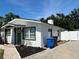 Exterior view of the white home with well-kept yard, concrete driveway, and bright blue skies at 4511 Hampshire Rd, Tampa, FL 33634