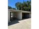 View of the detached garage and attached car port with open garage door and tan trim on a sunny day at 4511 Hampshire Rd, Tampa, FL 33634