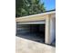View of the detached garage with partially open white garage door and tan trim on a sunny day at 4511 Hampshire Rd, Tampa, FL 33634
