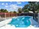 Swimming pool with safety fence, ladders, and chairs surrounded by green trees at 5968 46Th N Ave, Kenneth City, FL 33709
