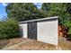 White shed with dark wooden door and stone foundation, nestled amongst lush landscaping at 5968 46Th N Ave, Kenneth City, FL 33709