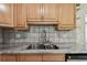 Close-up of kitchen sink featuring light wood cabinets, granite countertops, and tiled backsplash at 5968 46Th N Ave, Kenneth City, FL 33709