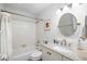 Bright bathroom with a round mirror, neutral vanity, and shower-tub combo at 6075 Shore S Blvd # 215, Gulfport, FL 33707
