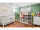 Bright, modern Bedroom with hardwood floors, white crib, and shelving unit featuring toys and books at 6137 Halifax Dr, New Port Richey, FL 34653