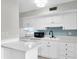 Bright kitchen featuring white cabinets, stainless appliances, and a stylish blue backsplash at 6400 46Th N Ave # 203, Kenneth City, FL 33709
