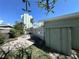 View of backyard with brick patio and garden bed, showcasing a tropical landscape and nearby high rise at 6407 1St Palm Pt, St Pete Beach, FL 33706