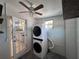 Compact laundry area featuring stacked washer/dryer, practical shelving, and natural light at 6407 1St Palm Pt, St Pete Beach, FL 33706