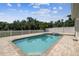 Backyard featuring a brick-lined pool and a white picket fence with mature trees in the background at 7246 Bucks Ford Dr, Riverview, FL 33578