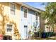 Townhouse with a blue front door, complemented by garden beds and lush shrubbery, in a row of colorful units at 7703 N Branch Ave, Tampa, FL 33604