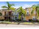 Street view of townhomes featuring colorful exteriors and lush palm trees at 7703 N Branch Ave, Tampa, FL 33604