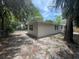 Exterior home view of the spacious backyard featuring mature trees, sunny skies, and a charming fence at 7831 Fox Hollow Dr, Port Richey, FL 34668