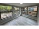 A sunroom with light colored laminate flooring, three large windows, and light gray paint at 7831 Fox Hollow Dr, Port Richey, FL 34668