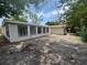 A sunroom with a tan exterior and a barren dirt yard at 7831 Fox Hollow Dr, Port Richey, FL 34668