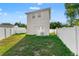 Backyard with a lush green lawn, white vinyl fencing, and a modern two-story home at 7911 N Packwood Ave, Tampa, FL 33604