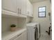 Laundry room with built-in cabinets, shelving, and modern washer and dryer at 8523 N Newport Ave, Tampa, FL 33604